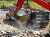 Backhoe placing construction materials in dumptruck