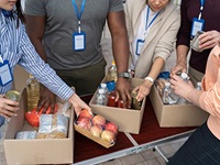 Hands reaching for various food in cardboard boxes