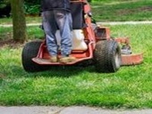 Person on standing riding lawnmower at commercial lot