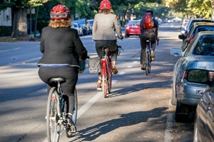Helmeted people ride bikes in the bike lanes